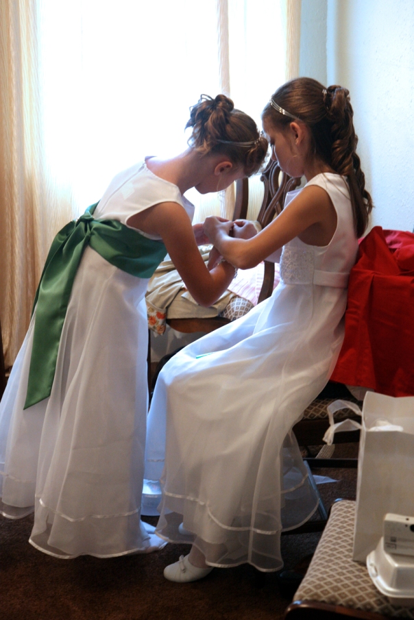 The junior bridesmaids help each other with their bracelets.